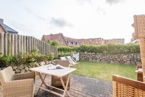 Eine Terrasse mit Korbmöbeln, einem Tisch und einer Steinmauer.