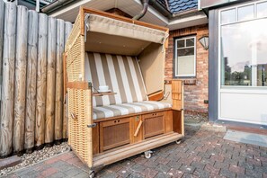 Un espace extérieur aménagé avec des sièges en bois, un banc rembourré et un auvent.