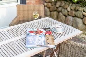 A table with a magazine, a glass of white wine, and a cup of coffee.