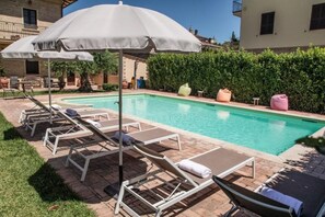 A swimming pool with lounge chairs and an umbrella. - Domus Angeli Camere (Assisi)