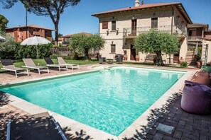 A swimming pool with lounge chairs and umbrellas, surrounded by a building with a balcony. - Domus Angeli Camere (Assisi)