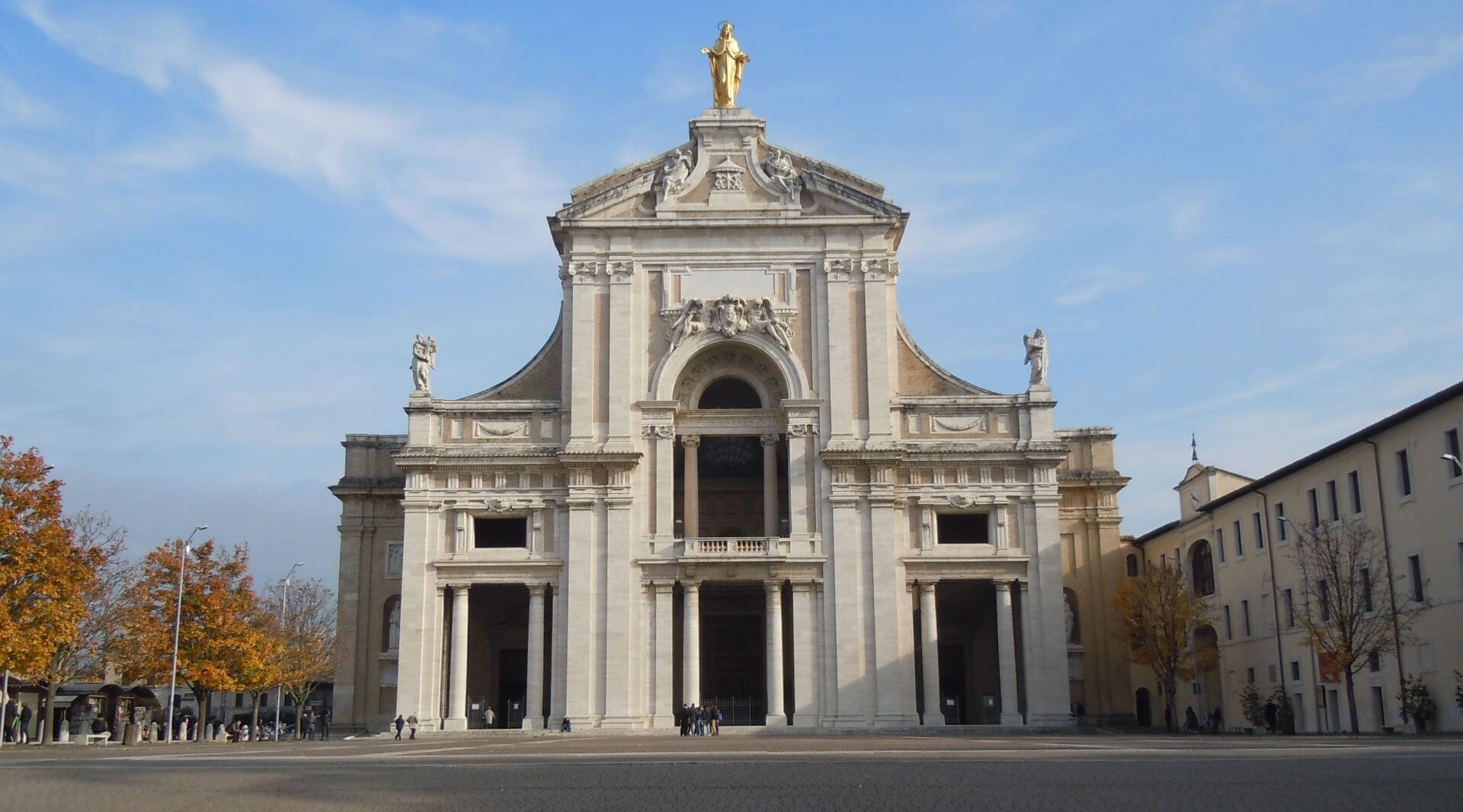 Um edifício imponente com um arco central, ladeado por colunas, e uma estátua no topo.