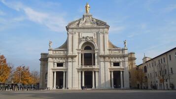 Um edifício imponente com um arco central, ladeado por colunas, e uma estátua no topo.