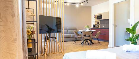 A modern hotel room with a bed, a desk, a sofa, and a dining area.