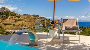 Un espace aménagé au bord de la piscine, comprenant une chaise, un parasol et une table agrémentée d’un objet décoratif.