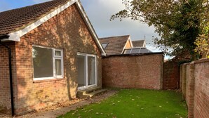 A brick house with a small lawn and a wooden deck. - 3-bed Bungalow Near Hayling Island Sailing Club (Hayling Island)