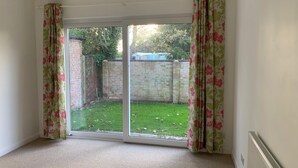 A room with a large sliding glass door leading to a grassy backyard. - 3-bed Bungalow Near Hayling Island Sailing Club (Hayling Island)