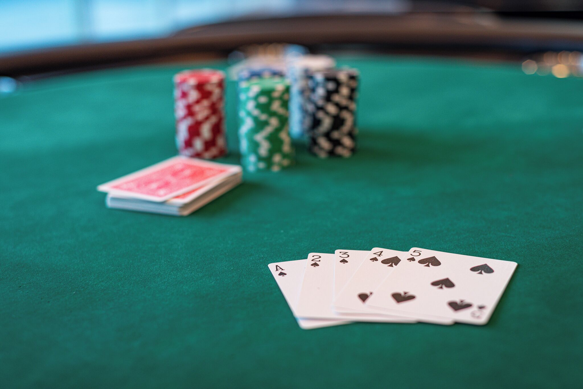 Una mesa de fieltro verde con cartas y fichas de póker.