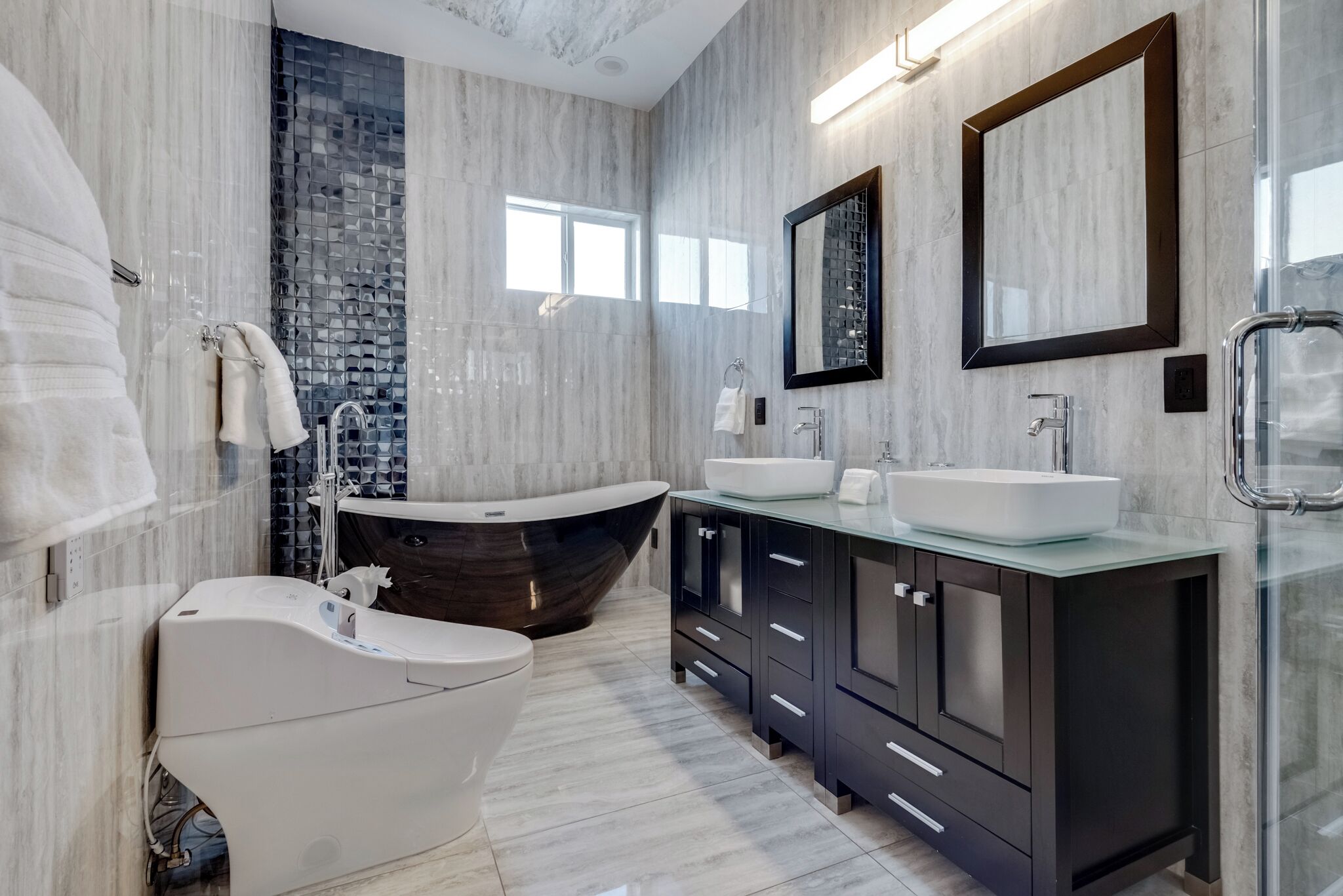 A modern bathroom with a freestanding bathtub, a double sink vanity, and a large mirror.