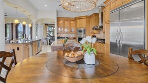 A spacious kitchen with wooden cabinets, a stainless steel refrigerator, and a dining area with a round table.