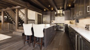 Cozinha moderna com armários de madeira escura, bancada de mármore e exaustor de aço inoxidável.