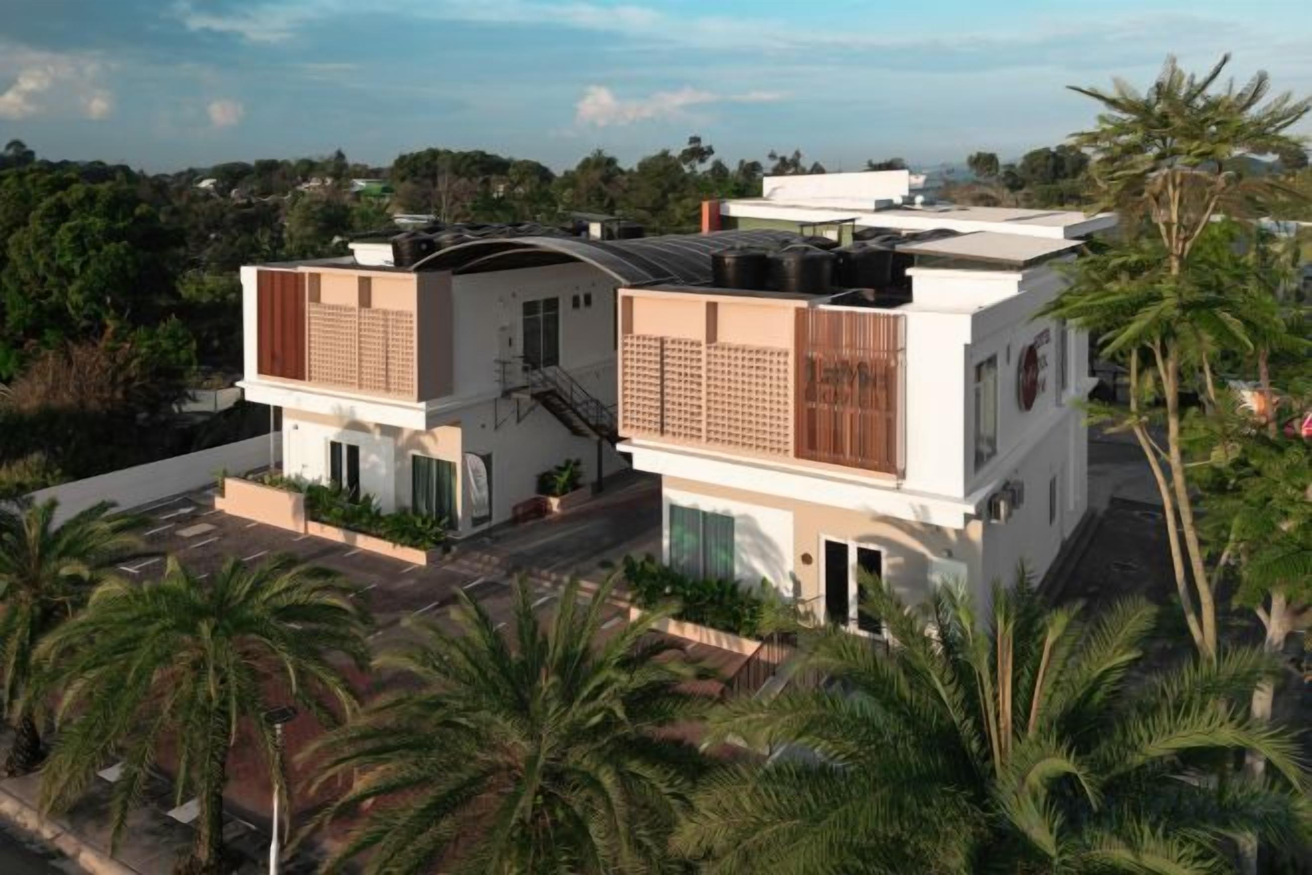 A modern two-story building with a flat roof, large windows, and a balcony.