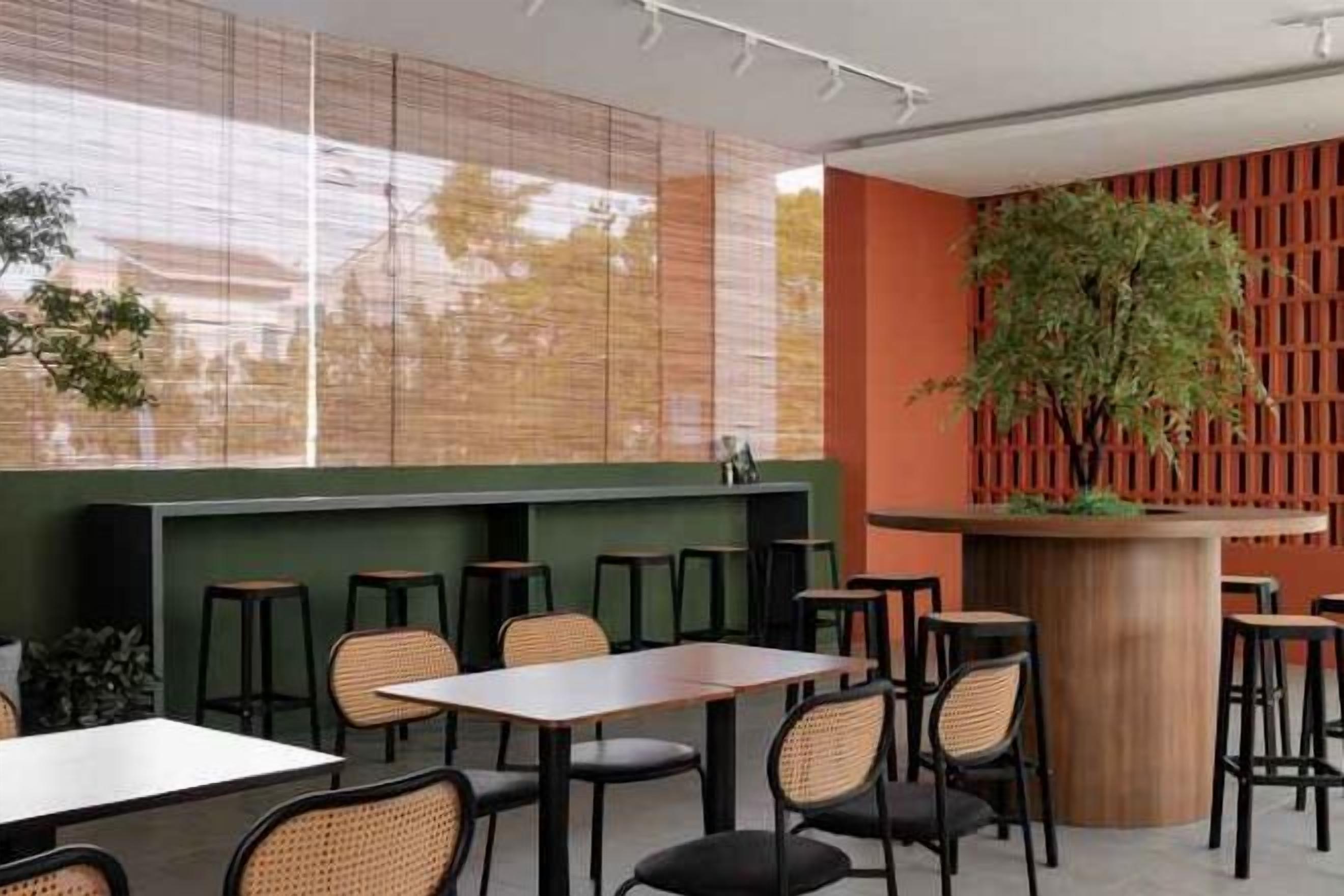 A restaurant interior with tables and chairs, a counter, and a large plant.