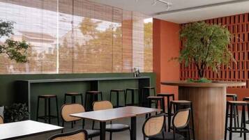 Un interior de restaurante con mesas y sillas, una barra y una planta grande.