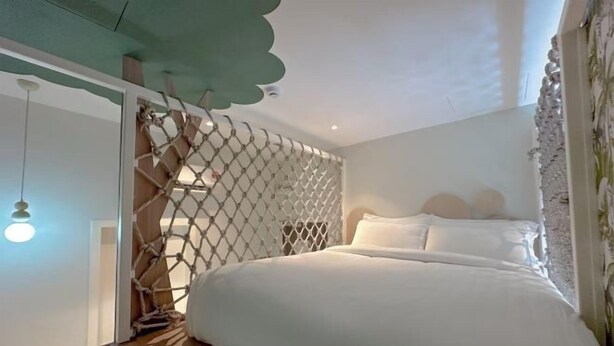 Ein Schlafzimmer mit einem Bett, einer Pendelleuchte und einer Zierwandverkleidung.