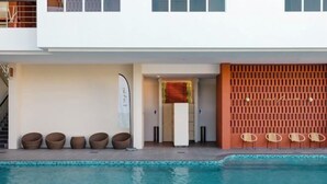 Ein modernes Gebäude mit Swimmingpool, Außenbereich und einer roten Wand mit Rasteroptik.