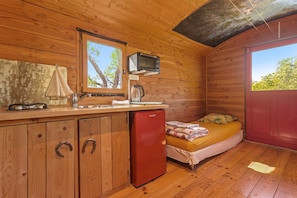 Ein kleines Holzhaus mit Küchenzeile, einem Bett und einem Fenster.