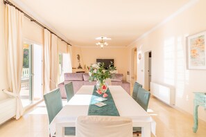 A dining area with a table, chairs, a vase with flowers, a sofa, and a television. - Villa 'Macondo Altea Hills' with Sea View, Wi-Fi and Air Conditioning (Altea)