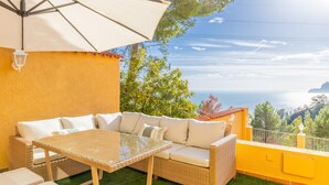 A balcony with a wicker sofa, a glass table, and a white umbrella. - Villa 'Macondo Altea Hills' with Sea View, Wi-Fi and Air Conditioning (Altea)