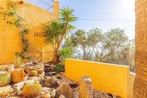 A yellow building with a cactus garden, a stone wall, and a view of trees. - Villa 'Macondo Altea Hills' with Sea View, Wi-Fi and Air Conditioning (Altea)