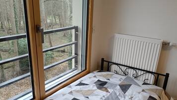 Une chambre avec un lit, de grandes fenêtres et un radiateur.