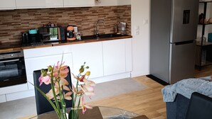 Una cocina moderna con armarios blancos, un refrigerador de acero inoxidable y una cafetera.