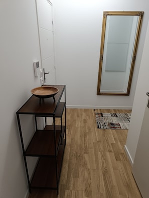 A bathroom with a wooden sink, a mirror with an ornate frame, and a patterned rug on the floor. - Apartment 'Chez Sibylle Chevreuse Saclay' with Balcony, Wi-Fi and Air Conditioning (Saint-Rémy-lès-Chevreuse)