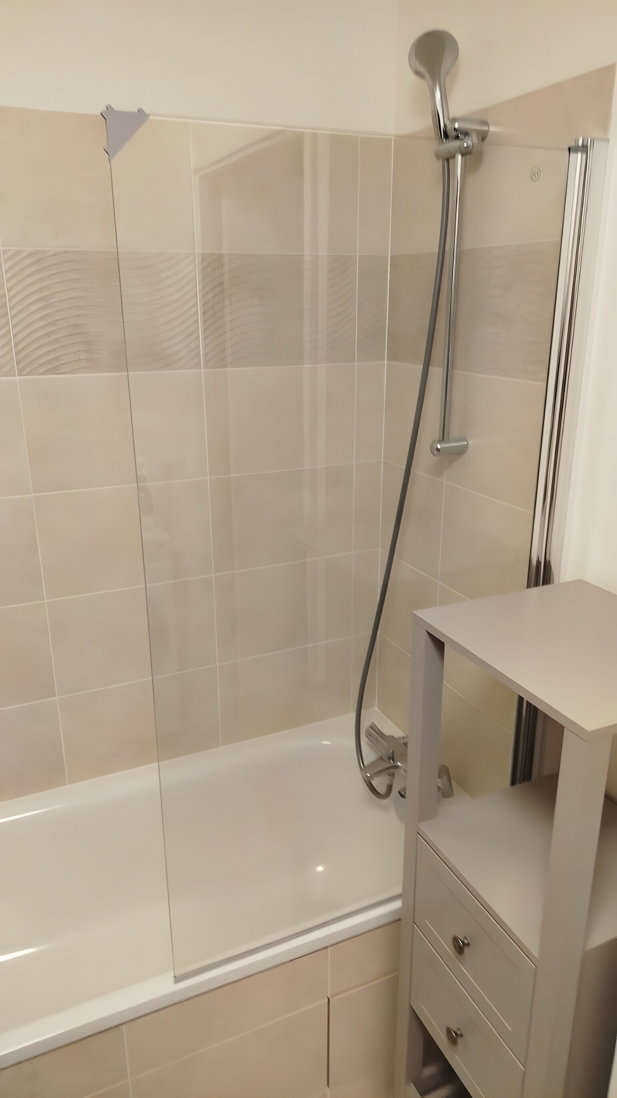 Een moderne badkamer met een douchecabine van glas, een bad en een wastafel met lades.