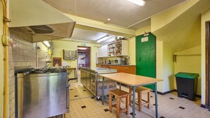 Una cocina con electrodomésticos de acero inoxidable, una mesa de madera y una puerta verde.
