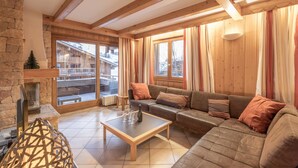 Un salon chaleureux avec une cheminée, un canapé, une table basse et de grandes fenêtres.