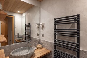 Une salle de bain avec un lavabo en pierre, un plan de toilette en bois, un porte-serviettes et un miroir.