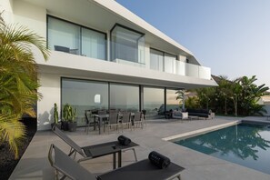 Una casa moderna con piscina, area relax all'aperto e ampie vetrate.