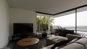 Ein modernes Wohnzimmer mit einem großen Flachbildfernseher, einem runden Couchtisch und einem Sofa.