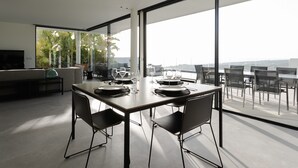Ein moderner Essbereich mit einem großen Tisch, gedeckt für vier Personen, umgeben von Stühlen, und einem Balkon mit Blick.