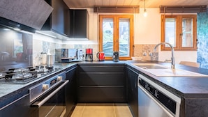 Una cocina moderna con estufa, horno y lavavajillas, armarios de madera y un ventanal con vistas.