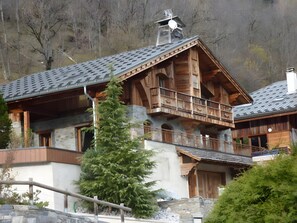 Un chalet en bois avec une façade en pierre, des balcons et une cheminée.