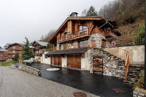 A rustic wooden house with a stone staircase and a balcony.