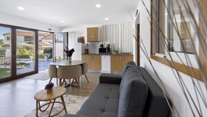A modern living space with a sofa, dining table, and kitchen area.
