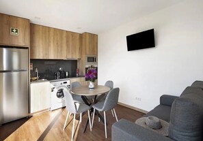 A modern kitchen with wooden cabinets, a stainless steel refrigerator, a microwave, and a washing machine. There's a dining table with chairs and a flat-screen TV mounted on the wall. - Holiday Home 'Villa with 4 Apartments' with Private Pool, Private Terrace and Wi-Fi Access (Apúlia)