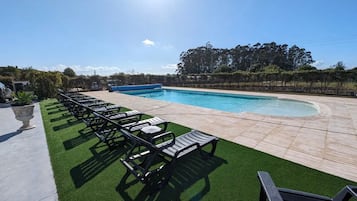 Ein Schwimmbecken mit Liegestühlen und Kunstgrasanlage.