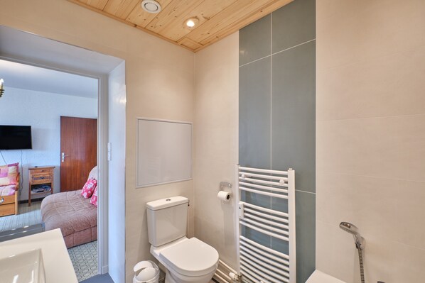 Un baño con inodoro, ducha, toallero y lavamanos.