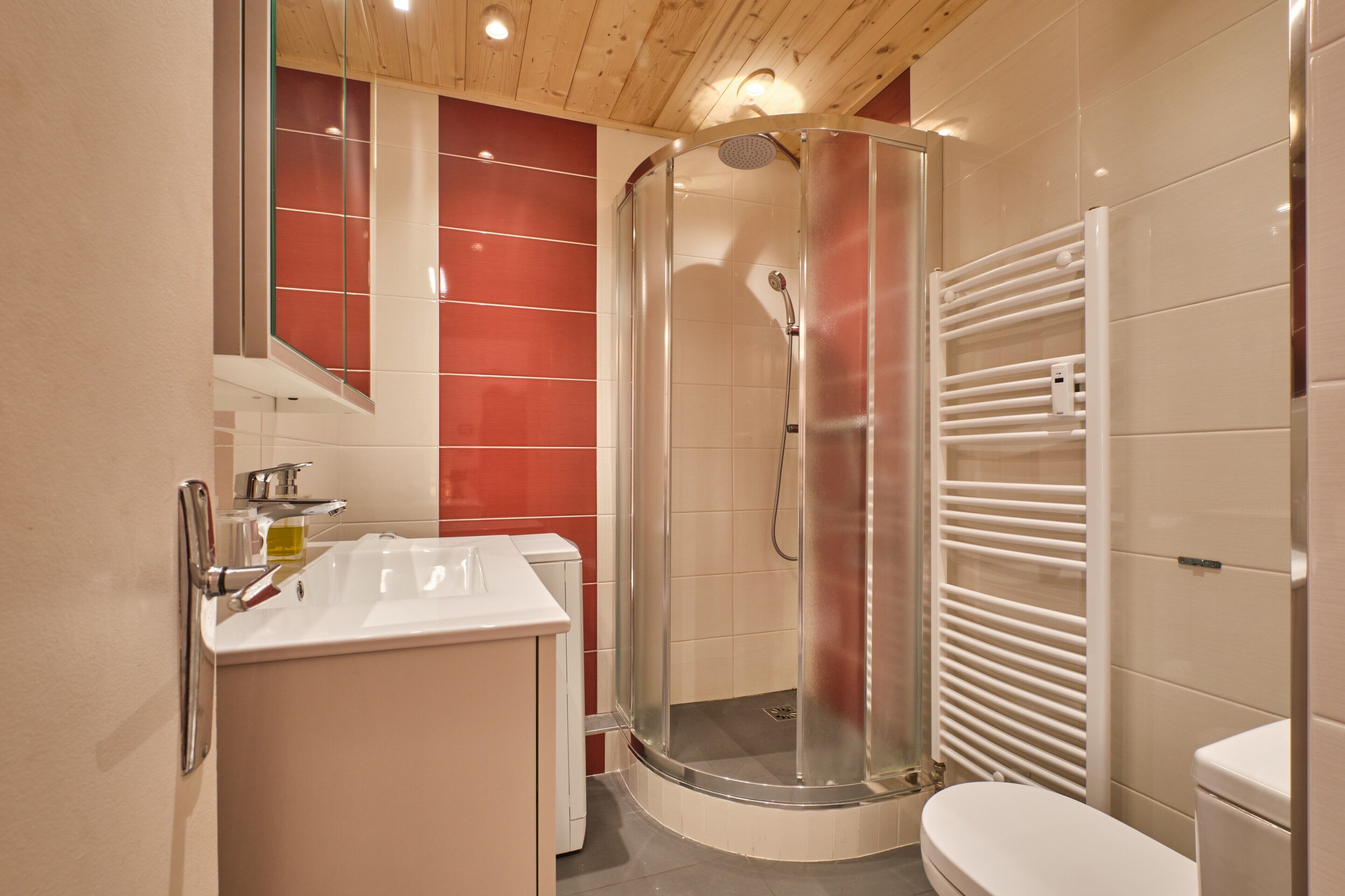 A modern bathroom with a glass-enclosed shower, a white sink, and a toilet.