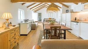 A spacious kitchen with wooden beams, a dining area, and a cozy seating space.