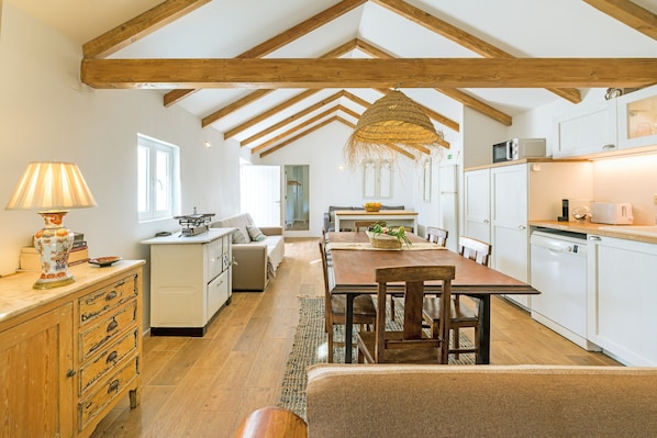 A spacious kitchen with wooden beams, a dining area, and a cozy seating space.