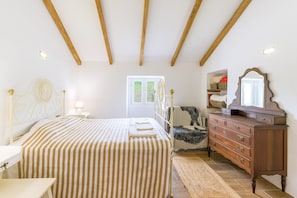 A bedroom with a bed, dresser, mirror, and window.