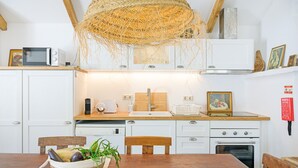 A kitchen with white cabinets, a microwave, a toaster, and a basket of vegetables on the table.