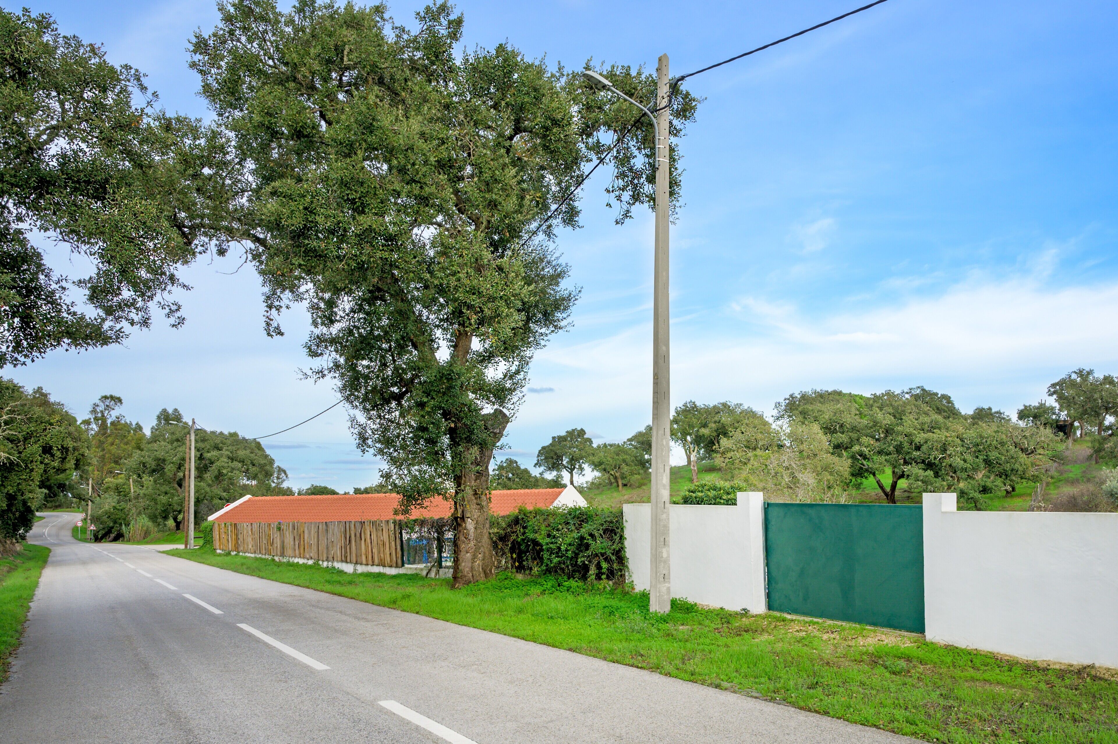 Eine ländliche Straße mit weißem und hölzernem Zaun sowie einem Gebäude mit rotem Dach.