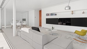 A modern living room with a sofa, a dining area with chairs, a kitchen, and a large black TV on the wall. - Vacation Villa 'Karat  Murano' with Sea View, Wi-Fi and Air Conditioning (Callao Salvaje)