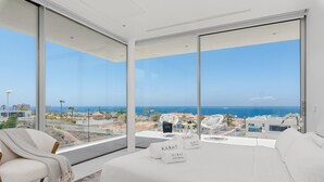 A modern room with a large window, a white sofa, and a chair. - Vacation Villa 'Karat  Murano' with Sea View, Wi-Fi and Air Conditioning (Callao Salvaje)
