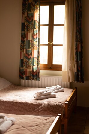 A bedroom with two beds, a window with curtains, and a radiator. - Guest House 'Armoloi Room 2' with Mountain View, Shared Terrace and Wi-Fi (Konitsa)